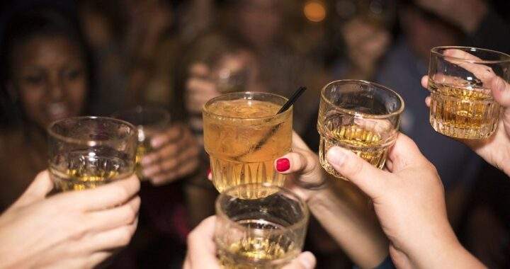 一群人在聚會中舉起酒杯慶祝展現經濟波動下消費者透過小額社交消費獲得情緒補償與心理慰藉的場景